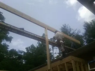 Carpenter setting a ridge beam over a new addition frame — Ice Dam Removal by Roofing Brothers in Mona