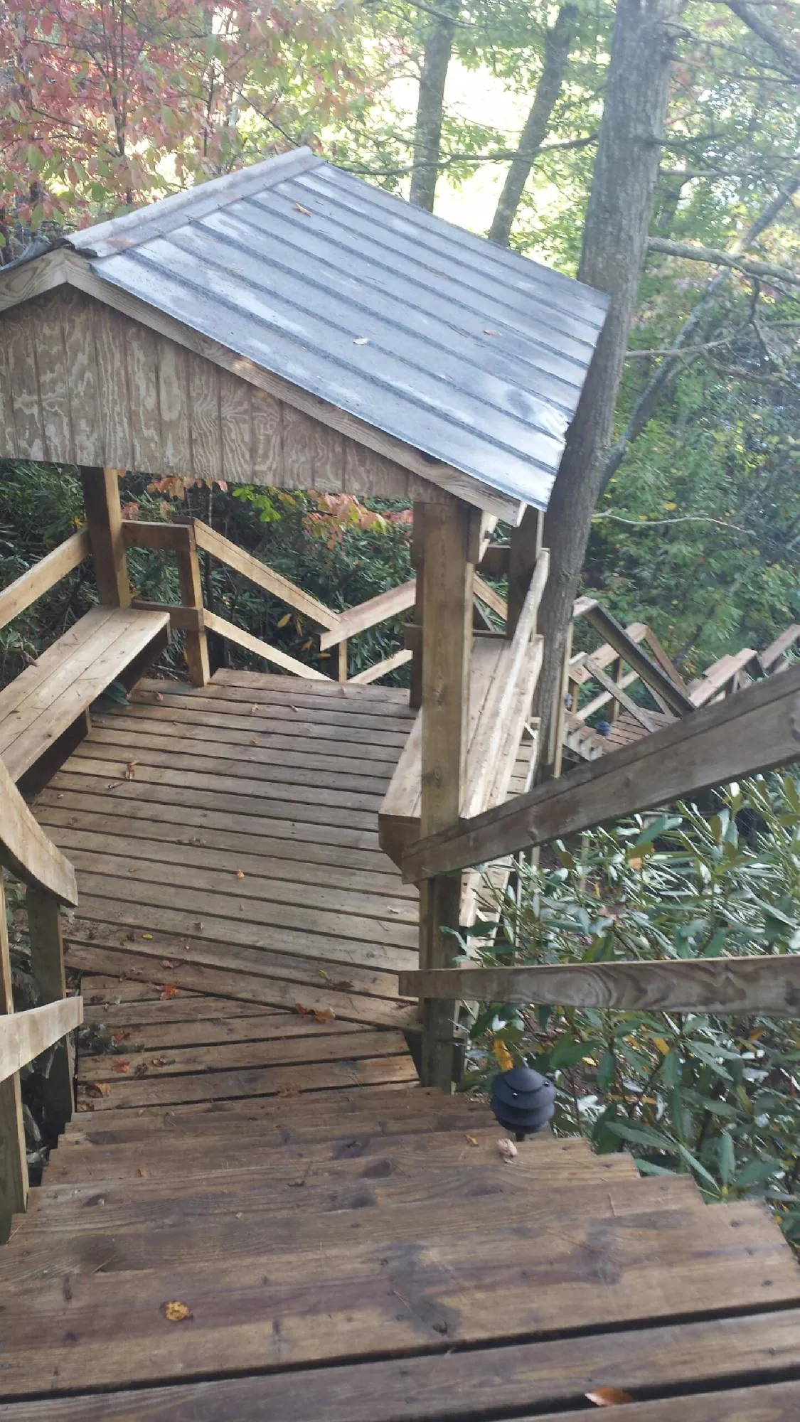 Metal roofed shelter over wooden steps on a wooded walkway — Skylight Repair & Installation work by our crew in Mona