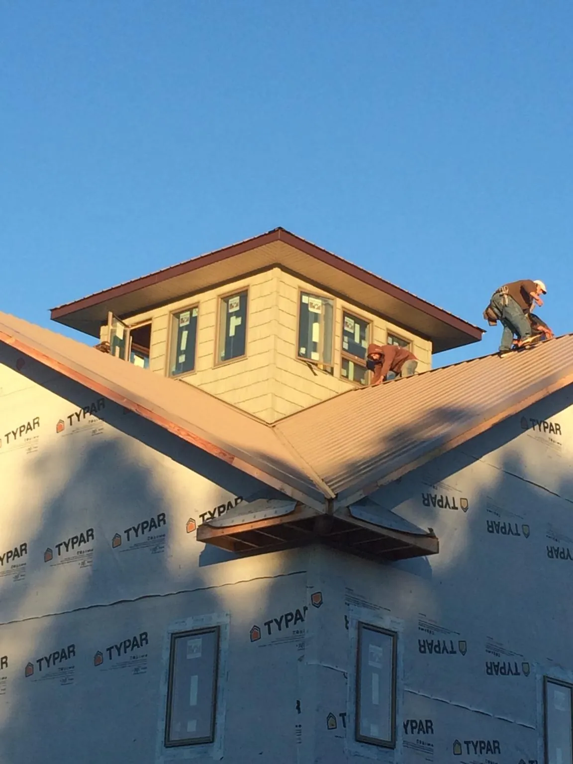 Roofers working around a rooftop cupola on a new metal roof at sunset — Roof Waterproofing in Mona by Roofing Brothers